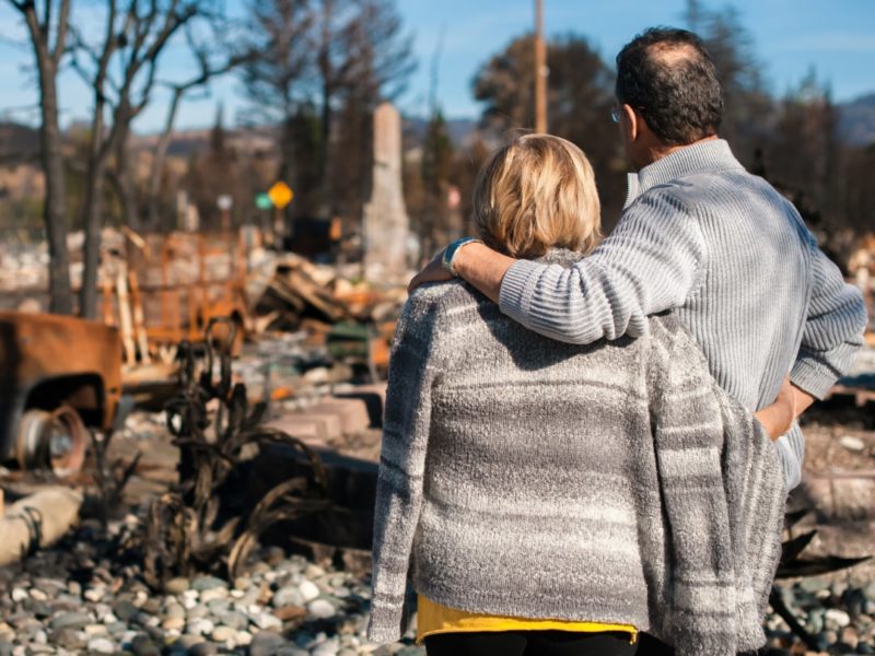 A homeowner and his wife checking a ruined house and yard after a fire disaster.