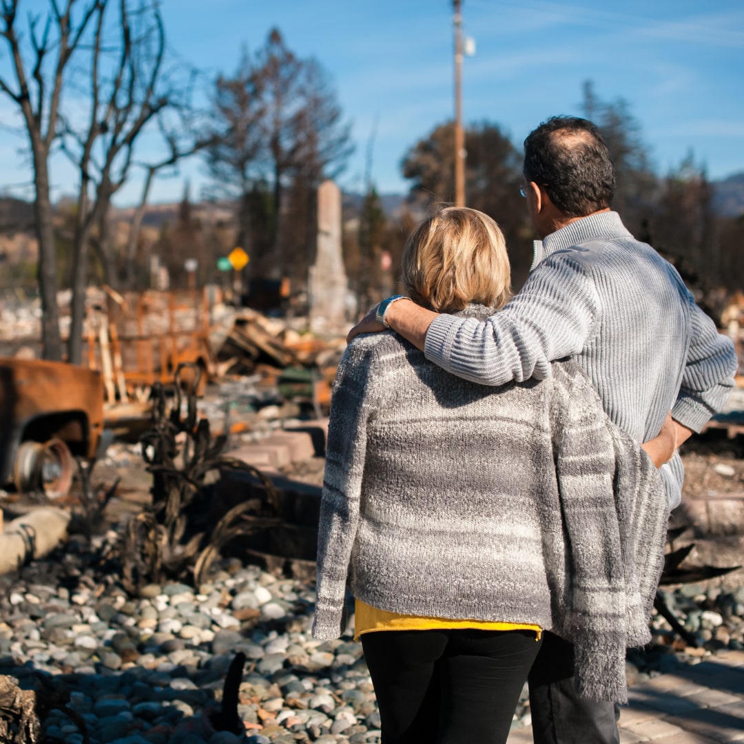 A homeowner and his wife checking a ruined house and yard after a fire disaster.