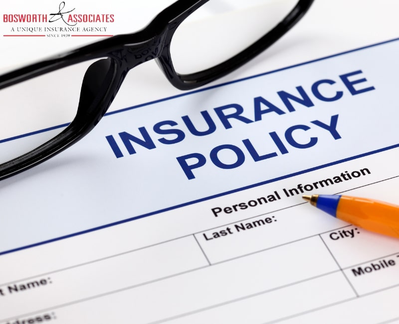 An insurance policy form with glasses and a pen.