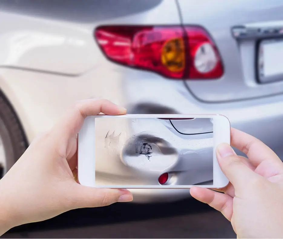 Person taking a photos on their smartphone of car damage from a car accident