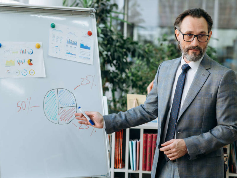male salesperson in front of a whiteboard with stats
