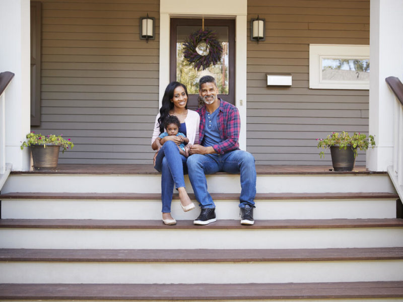 family sitting on the front porch of their home