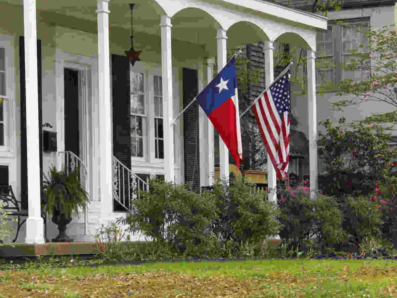 quaint Texas home with the Texas and American flags flying from the front porch
